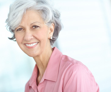 Woman with gray hair in pink shirt smiling