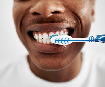 Closeup of man smiling while brushing his teeth