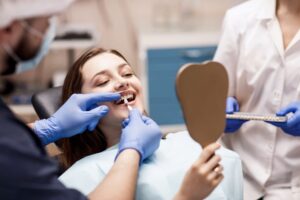 Patient having veneer applied while looking into the mirror in dentist's chair.