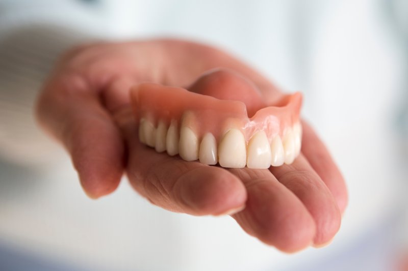 A hand holding an upper removable denture